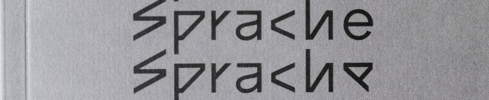 Das Buchcover besteht vorwiegend aus dem Wort „Sprache“, schwarz auf dunkelgrau, mehrfach untereinander geschrieben. Auf jeder neuen Zeile gleicht die verwendete Schriftart, die zuoberst noch eine serifenlose Schrift ist im Stil von Arial ist, germanischen Runen. Die Anspielung ist wohl klar. Hier werden nur die beiden letzten Zeilen des Covers gezeigt, wo also die Transformation in Runen praktisch vollständig ist.